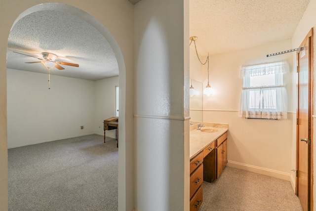 bathroom with ceiling fan, vanity, and a textured ceiling