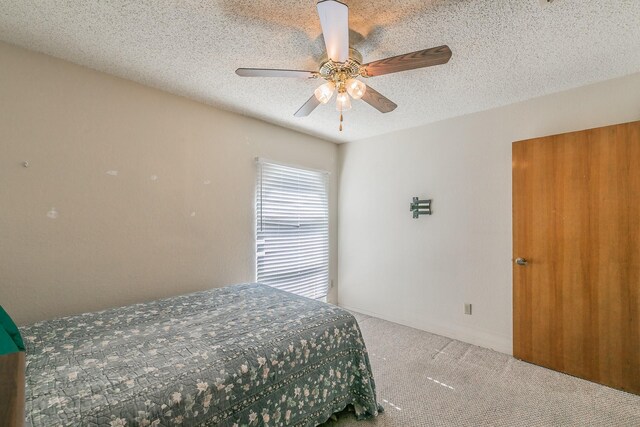 carpeted bedroom with ceiling fan and a textured ceiling