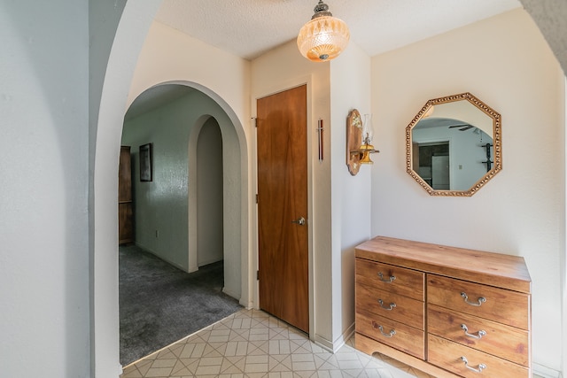 corridor featuring light colored carpet and a textured ceiling