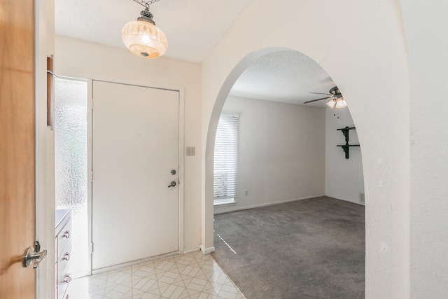 carpeted foyer with ceiling fan and a textured ceiling