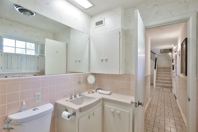 bathroom featuring vanity, backsplash, toilet, and tile walls