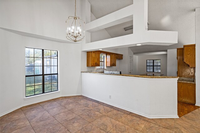 kitchen featuring high vaulted ceiling, a notable chandelier, kitchen peninsula, a textured ceiling, and decorative light fixtures