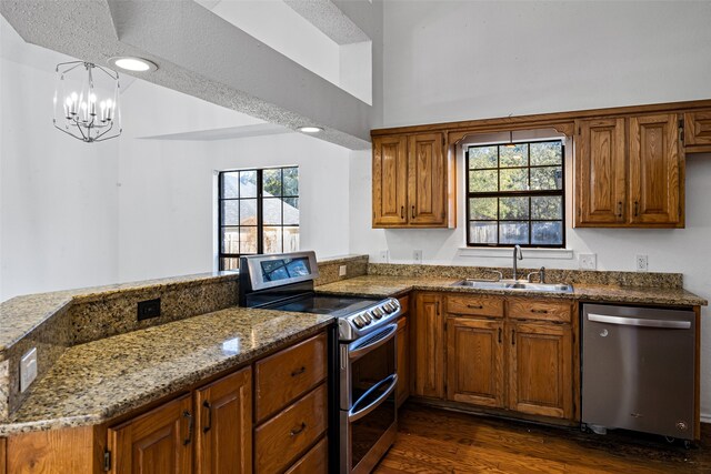 4007 Frisco Ct, Granbury, TX 76048 - kitchen featuring appliances with stainless steel finishes, a sink, a peninsula, dark wood-style floors, and brown cabinetry
