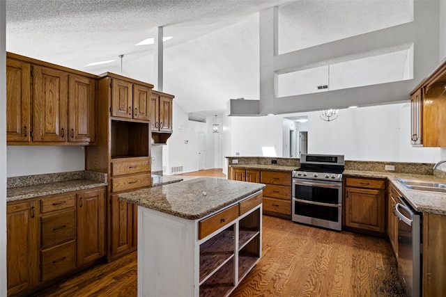 kitchen with kitchen peninsula, appliances with stainless steel finishes, vaulted ceiling, sink, and hardwood / wood-style flooring