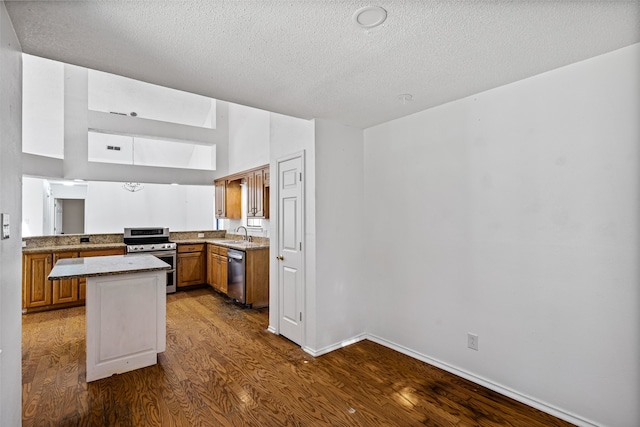 4007 Frisco Ct, Granbury, TX 76048 - kitchen featuring stainless steel appliances, dark wood-style flooring, a textured ceiling, brown cabinetry, and a center island