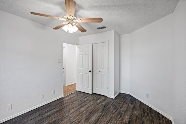 unfurnished bedroom featuring ceiling fan, dark hardwood / wood-style flooring, and a textured ceiling