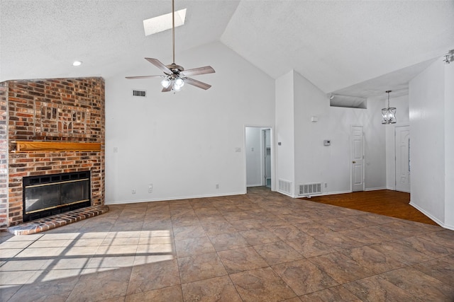 unfurnished living room with a skylight, a brick fireplace, a textured ceiling, ceiling fan, and high vaulted ceiling