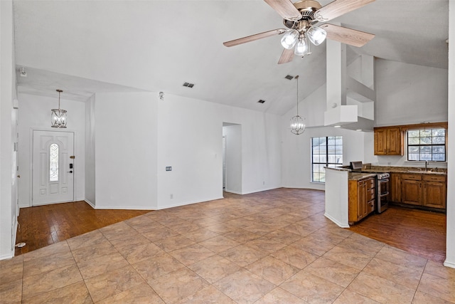 kitchen featuring kitchen peninsula, ceiling fan with notable chandelier, sink, electric stove, and light hardwood / wood-style floors