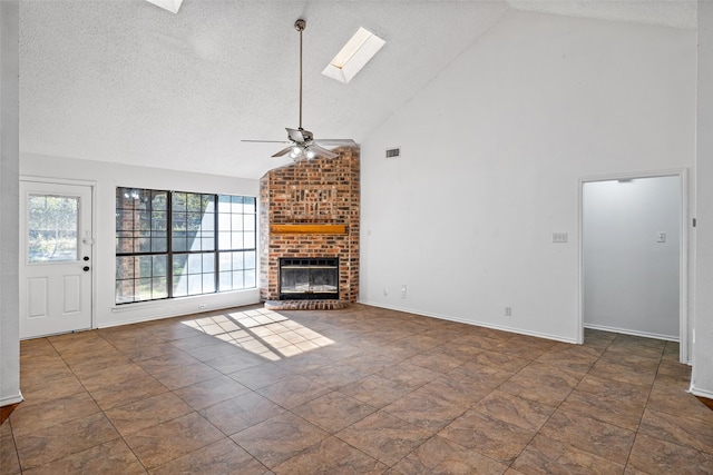 unfurnished living room with a skylight, ceiling fan, a brick fireplace, high vaulted ceiling, and a textured ceiling