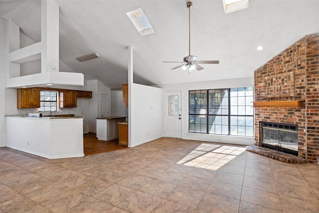 4007 Frisco Ct, Granbury, TX 76048 - unfurnished living room with vaulted ceiling, a skylight, ceiling fan, a fireplace, and a textured ceiling