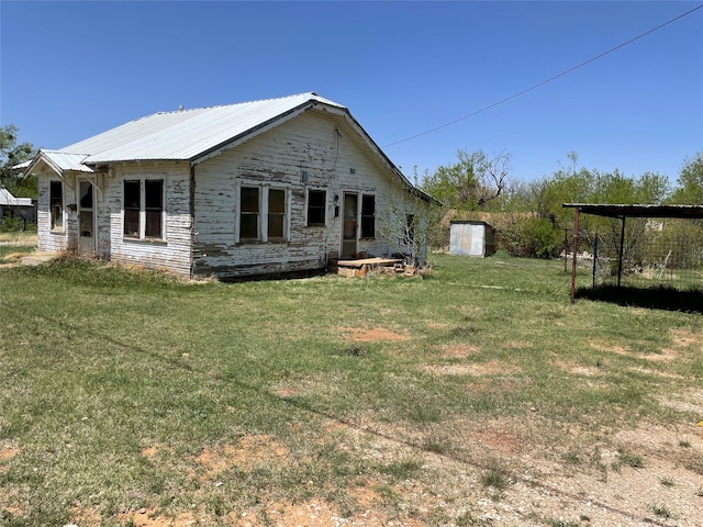 back of property with a storage shed and a lawn