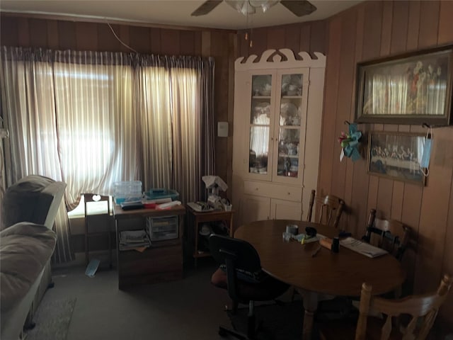 dining area featuring ceiling fan, carpet floors, and wood walls