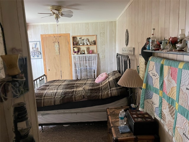 carpeted bedroom featuring ceiling fan and wooden walls