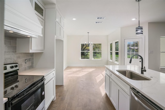 kitchen featuring sink, stainless steel appliances, an inviting chandelier, backsplash, and white cabinets