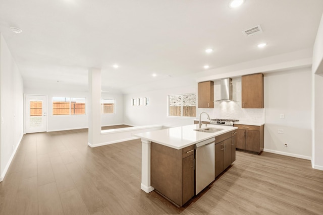 kitchen featuring a sink, visible vents, open floor plan, stainless steel dishwasher, and wall chimney exhaust hood