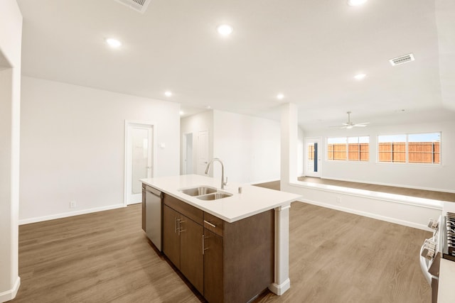 kitchen with visible vents, an island with sink, light wood-style flooring, stainless steel appliances, and a sink