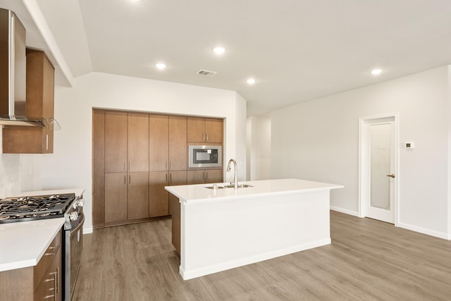 kitchen featuring stainless steel gas range oven, visible vents, brown cabinetry, built in microwave, and a sink