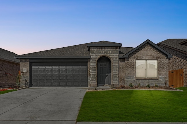 view of front facade featuring driveway, brick siding, an attached garage, and a front yard