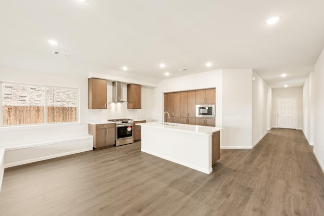 kitchen with visible vents, light countertops, appliances with stainless steel finishes, wall chimney exhaust hood, and brown cabinetry