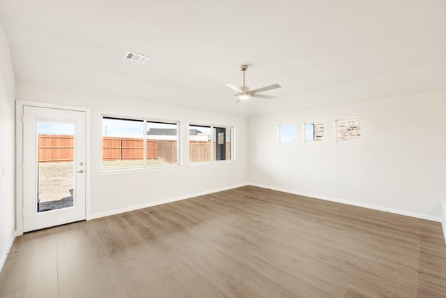 unfurnished room featuring baseboards, visible vents, ceiling fan, and wood finished floors