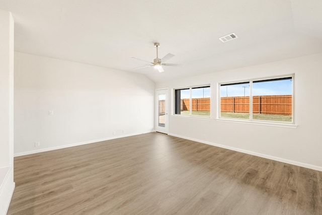 unfurnished room featuring lofted ceiling, wood finished floors, a ceiling fan, visible vents, and baseboards