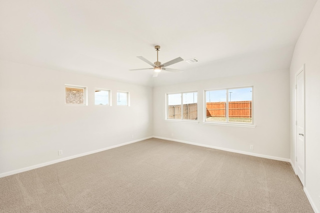 carpeted empty room featuring a ceiling fan, visible vents, and baseboards