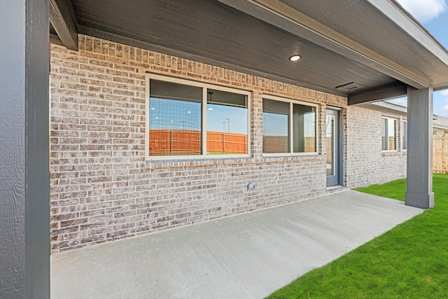 view of property exterior with a patio and brick siding