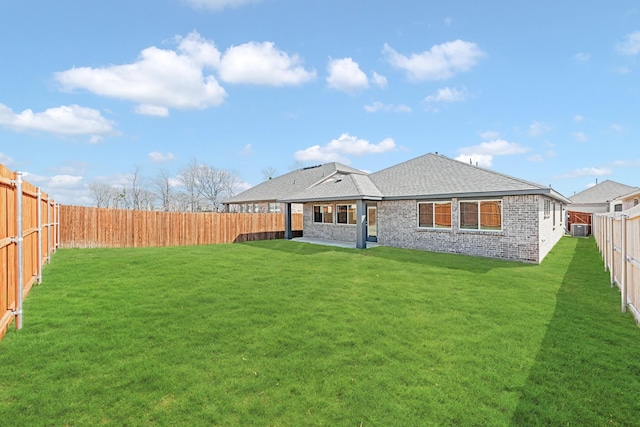 back of house featuring brick siding, a fenced backyard, roof with shingles, and a yard