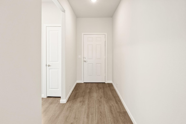 hall featuring light wood-type flooring and baseboards