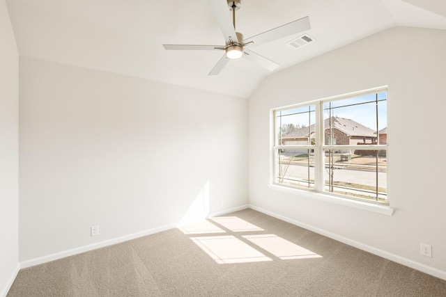 carpeted spare room with a ceiling fan, visible vents, vaulted ceiling, and baseboards