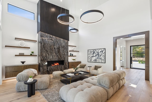 living room featuring a high end fireplace, light hardwood / wood-style floors, and a high ceiling