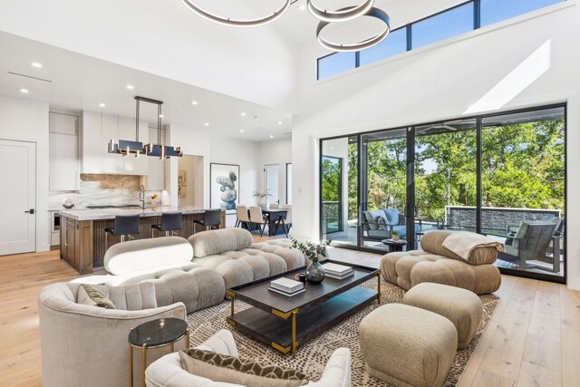 living room with a chandelier, a high ceiling, and light wood-type flooring