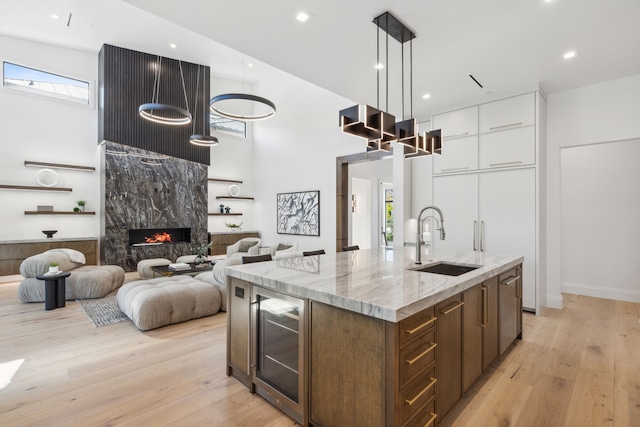 kitchen featuring plenty of natural light, sink, beverage cooler, and an island with sink