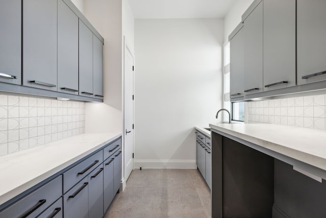 kitchen featuring decorative backsplash, gray cabinets, and sink