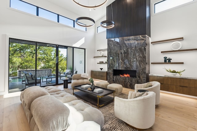 living room featuring light hardwood / wood-style floors, a healthy amount of sunlight, and a high ceiling