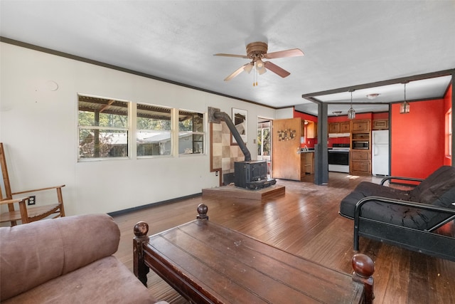 living room with a wood stove, ceiling fan, crown molding, and hardwood / wood-style flooring