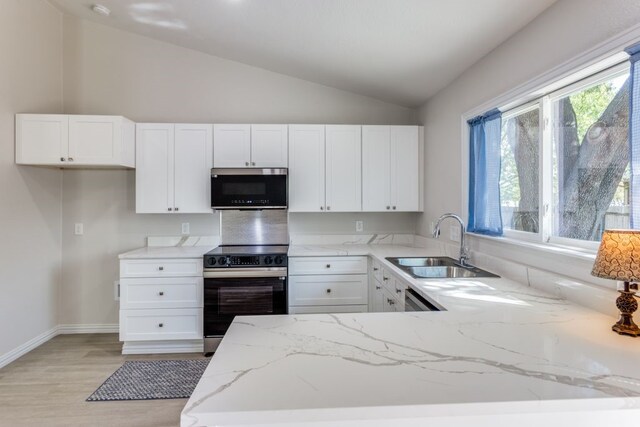 kitchen featuring appliances with stainless steel finishes, light stone counters, vaulted ceiling, sink, and white cabinetry