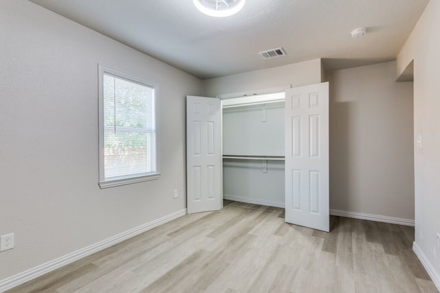 unfurnished bedroom featuring light wood-type flooring and a closet