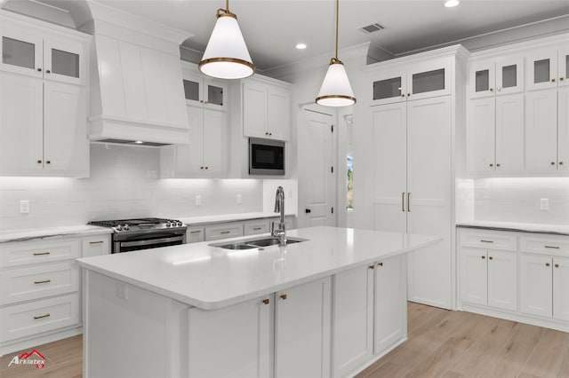 kitchen featuring appliances with stainless steel finishes, sink, light hardwood / wood-style flooring, white cabinetry, and hanging light fixtures