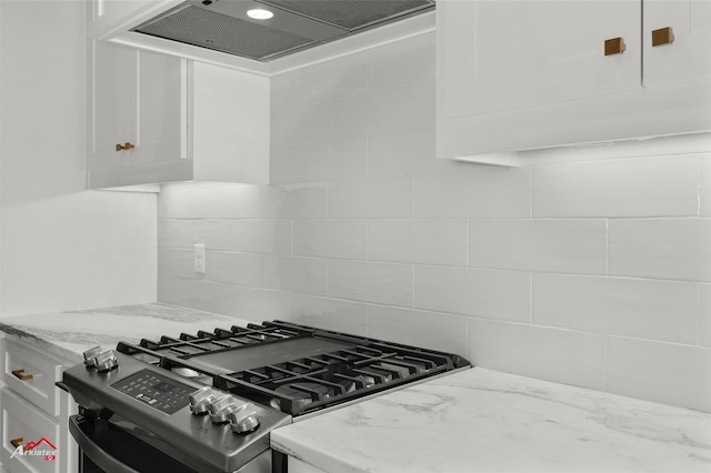 kitchen featuring gas range, white cabinetry, light stone countertops, tasteful backsplash, and extractor fan