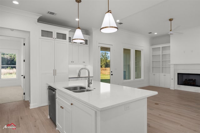 kitchen featuring white cabinets, sink, an island with sink, and hanging light fixtures