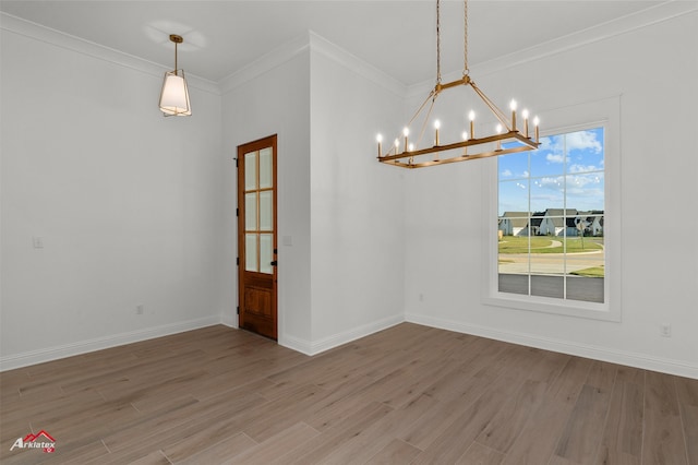 unfurnished dining area with wood-type flooring, crown molding, and a notable chandelier