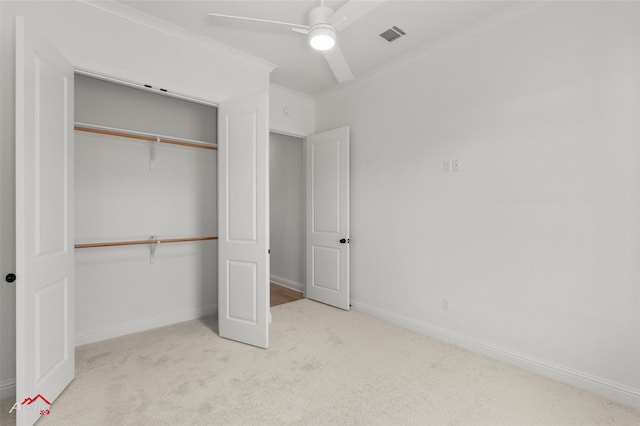 unfurnished bedroom with ceiling fan, light colored carpet, crown molding, and a closet