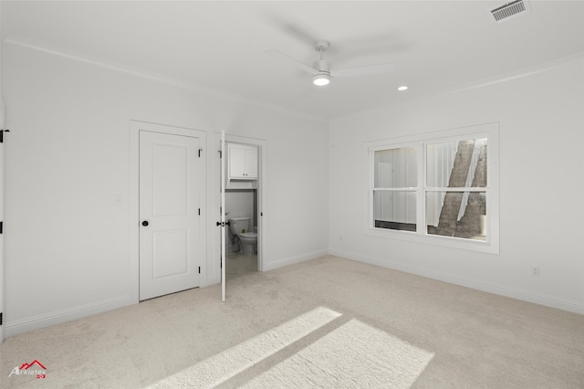 unfurnished bedroom with ensuite bath, ceiling fan, and light colored carpet