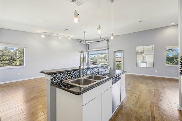 kitchen with white cabinets, a center island with sink, dishwasher, and light hardwood / wood-style floors