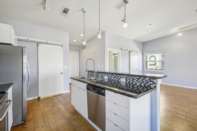 kitchen featuring white cabinetry, sink, a barn door, and stainless steel appliances