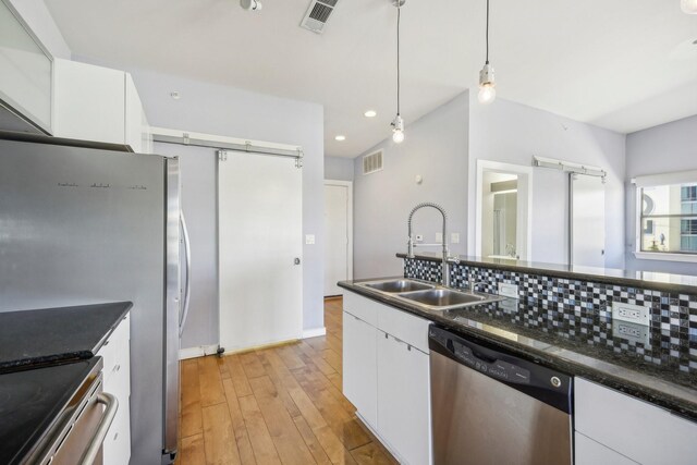 kitchen with sink, appliances with stainless steel finishes, decorative light fixtures, white cabinets, and light wood-type flooring