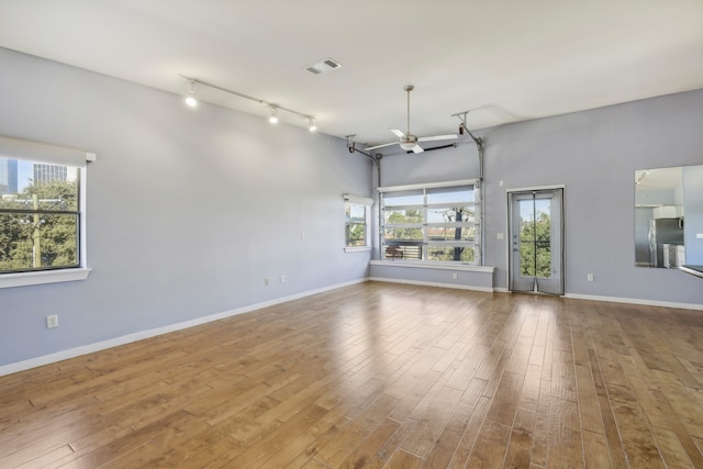 spare room with rail lighting, ceiling fan, and light wood-type flooring