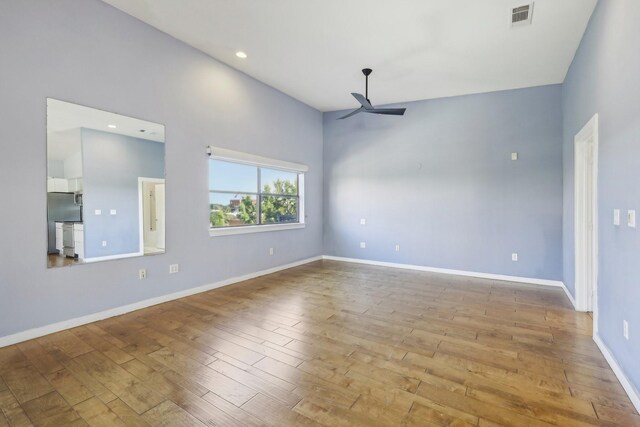 empty room featuring high vaulted ceiling, ceiling fan, and light wood-type flooring