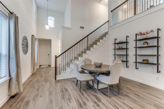 dining room with a towering ceiling and light hardwood / wood-style floors